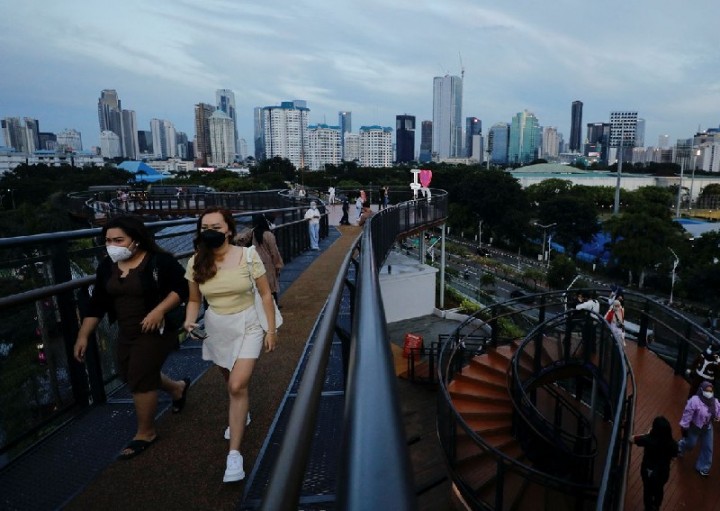 Orang-orang yang memakai masker pelindung menikmati berjalan-jalan di sepanjang jembatan skywalk saat varian virus corona Omicron terus menyebar, di Jakarta, Indonesia, pada 7 Februari 2022. Reuters