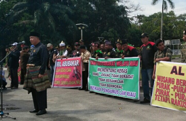 Sejumlah massa membentangkan spanduk protes saat Syarwan Hamid kembalikan gelar ke LAM Riau (foto/riki) 