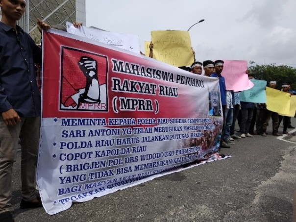 Massa petani sawit dari Rohil membentangkan spanduk saat aksi di pintu gebang Mapolda Riau,  Kamis 20 Desember 2018 siang. Foto: hadi 