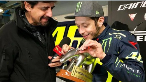 Rossi tersenyum sambil memegang kuping Tropi yang baru diterimanya.