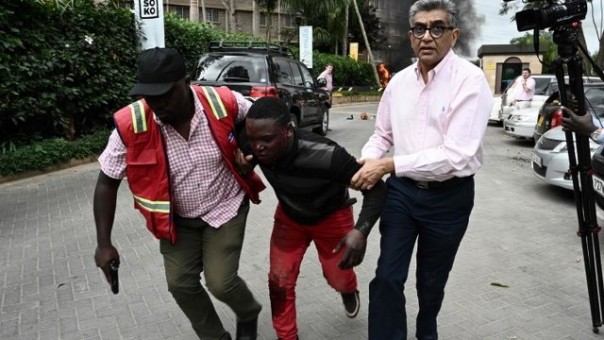Foto dari AFP memperlihatkan petugas Kepolisian membantu membawa seorang pria yang terluka menjauh dari hotel yang diserbu sejumlah pria bersenjata. Foto: int 