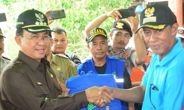 Bupati Inhil HM Wardan menyerahkan bantuan kepada warga yang menjadi korban bencana tanah longsor di Desa Sungai Nyiur, Kecamatan Tanah Merah. Foto: ist 