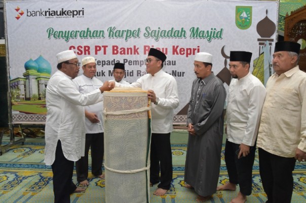 Dirut Bank Riau Kepri, DR Irvandi Gustari saat menyerahkan karpet sajadah kepada Gubernur Riau, Wan Thamrin Hasyim