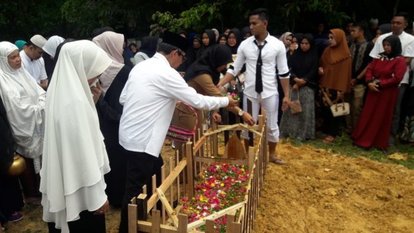 Bupati Kuansing H. Mursini saat melakukan penaburan bunga saat di makam jenazah Fitria Arini, S.STP/zar