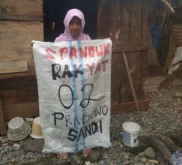 Seorang ibu memegang spanduk Prabowo-Sandi terbuat dari karung (foto/int) 