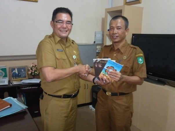 Kepala Dinas Perpustakaan dan Kearsipan,  Drs H Ismail Arsyad MSi menerima sumbangan buku dari penulis/int