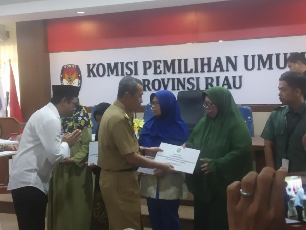 Didamping ketua KPU Riau Ilham M Yasir gubernur Riau Syamsuar serahkan bantuan kepada petugas Pemilu yang meninggal dunia