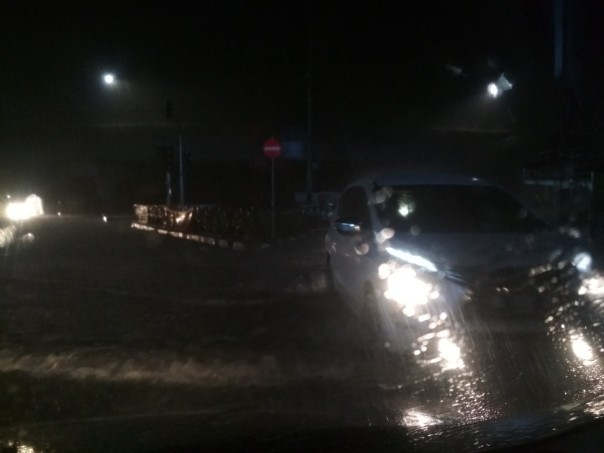 Terlihat sebuah mobil putih mogok di tengah hujan lebat dan banjir yang melanda Pekanbaru, Selasa malam.