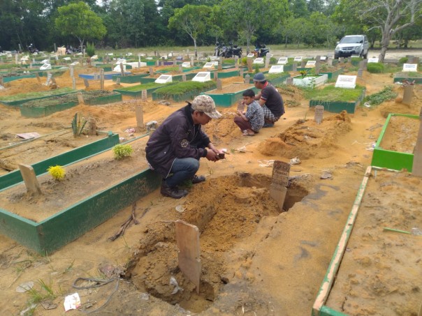 Terlihat salah seorang peziarah tengah melihat makam kerabatnya yang ikut amblas, diduga karena faktor hujan deras yang melanda Pekanbaru dua hari belakangan.