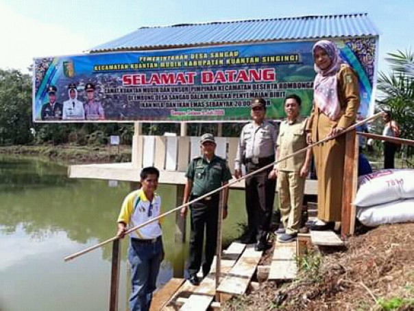 Camat Kuantan Mudik Sadarisnah, didampingi Plt. Kades Sangau Darmawan saat meresmikan dan penyebaran Benih ikan di Embung Desa Sangau/zar