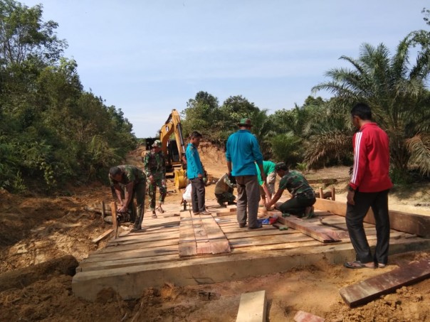 Satgas TMMD ke 105 Kodim 0313/KPR saat membantu masyarakat membangun jembatan penyeberangan di Desa Balung, Kabupaten Kampar