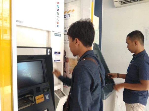 Nasabah Bank Mandiri mencoba melakukan transaksi di ATM/hari