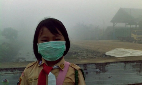 Anak sekolah pakai masker di tengah kabut asap pekat (foto/ilustrasi)