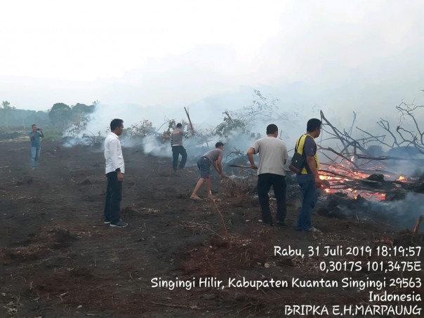 Personel Polsek Singingi Hilir sedang melakukan pemadaman terhadap lahan yang terbakar di Singingi Hilir/zar