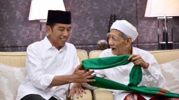  Jokowi saat menerima pemberian sorban berwarna hijau dan Mbah Moen./ foto:kumparan