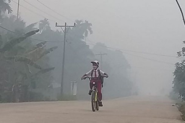 Seorang siswa bersepeda dengan kondisi kabut asap tebal. Foto: int 