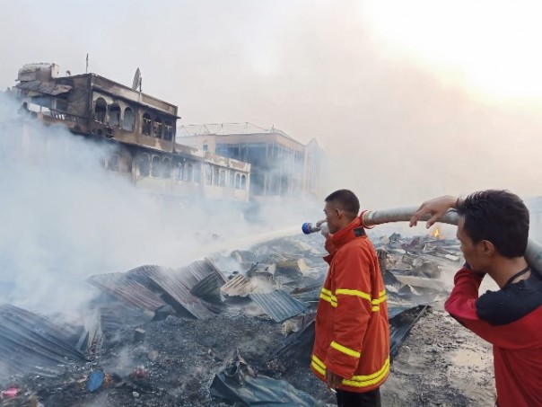 Petugas masih berupaya memadamkan sisa-sisa api yang membakar Pasar Selodang Kelapa di Tembilan, yang musnah terbakar Kamis dini hari tadi. Foto: rgo 