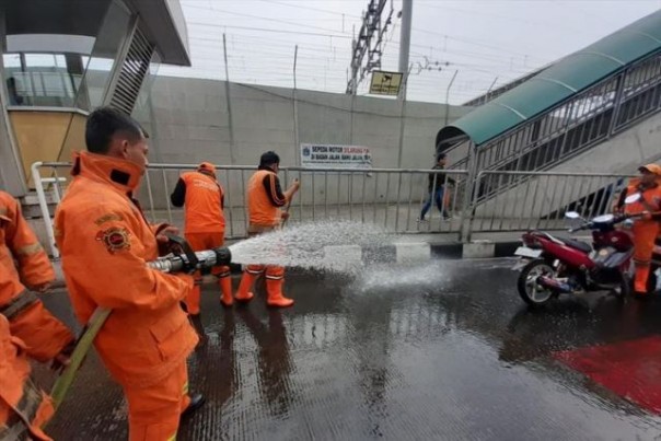 Sejumlah petugas Damkar dan ishub DKI menyirami trotoar di Stasiun MRT Lebak Bulus, Jakarta Selatan, yang dikeluhkan warga karena mengeluarkan bau pesing. Foto: int 