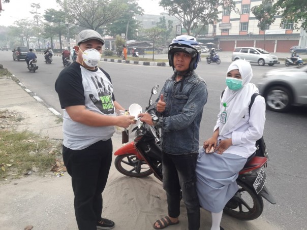 Ketua PWI Riau H Zulmansyah Sekedang membagikan masker kepada salah seorang pengendara sepeda motor di depan Gedung PWI Riau, Pekanbaru, Selasa (10/9/2019)./IST