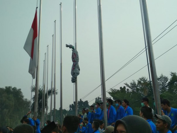 Mahasiswa mengantungkan pocong pada tali bendera kantor DPRD Riau sebagai protes kabut asap