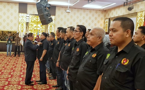 Ketua KONI Riau,  Emrizal Pakis memasang pin kepada Ketua KONI Meranti,  Hendrizal,  alias Bocang/mad