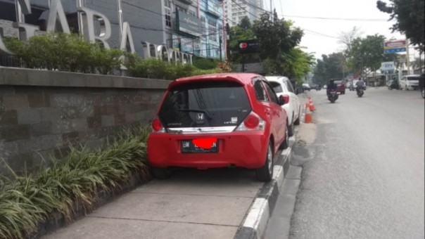 Dinas Perhubungan (Dishub) Kota Pekanbaru mengusir dua mobil yang 'memanjat' atas trotoar depan Hotel Megara Jalan Ahmad Yani (foto/riki)