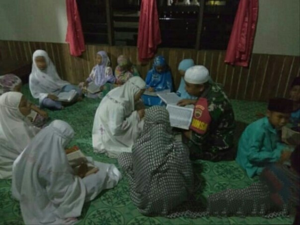 Babinsa Desa Simpang Gaung mendampingi baca Alquran bersama dalam kegiatan Magrib mengaji (foto/Rgo)