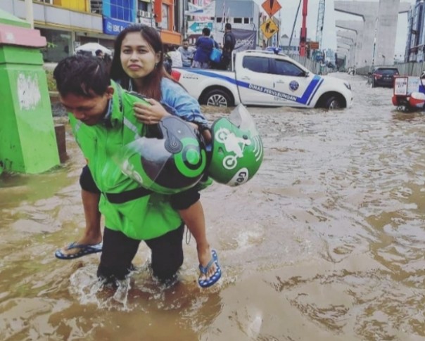 Ojol gendong perempuan di tengah banjir (foto/int)