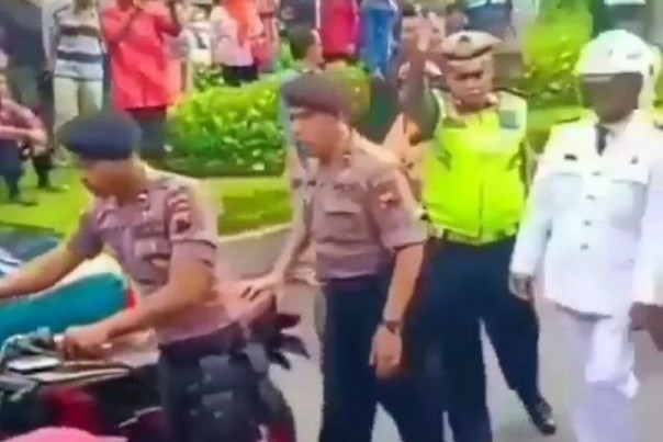 Dua petugas Kepolisian mengamankan sepeda motor miik seorang kades, sedangkan sang pemilik ikut di belakangnya. ***