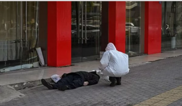 Petugas memeriksa jasad pria yang meninggal di trotoar jalan di Kota Wuhan, yang diduga akibat virus Corona. Foto: int  