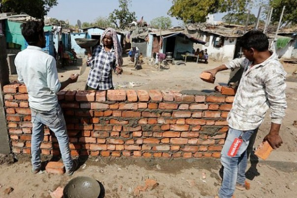 Pekerja di Gujarat, India, membangun tembok yang tujuannya disebut-sebut untuk menutup kawasan pemukiman kumuh saat kunjungan Presiden AS Donald Trump. Foto: int  