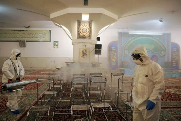 Petugas di Iran menyemprotkan cairan desinfektan di salah satu tempat umum. Foto: int 