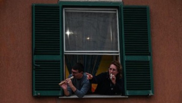 Penduduk Italia yang bermukim di Roma bernyanyi di jendela rumah demi mengusir bosan akibat isolasi virus corona. (AFP/ANDREAS SOLARO)