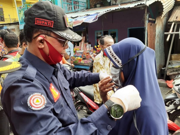 Bupati Rokan Hilir Suyatno memasangkan masker gratis ke warga Kelurahan Bagan Hulu, Kecamatan Bnagko (foto/ist)