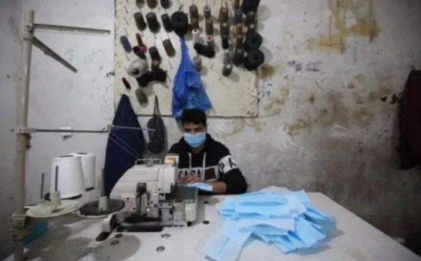 Seorang pekerja di Gaza menjahit masker