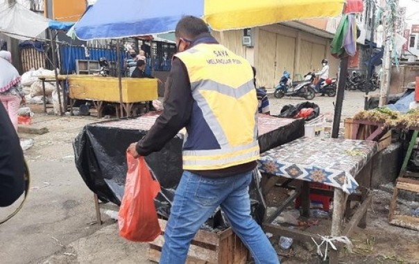 Warga yang diberi sanksi membersihkan pasar karena kedapatan tak menggunakan masker. Foto: int