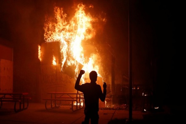 Seorang demonstran menyaksikan pembakaran sebuah fasilitas di Minneapolis,, Minnesota, Amerika Serikat, 29 Mei 2020. Foto/REUTERS