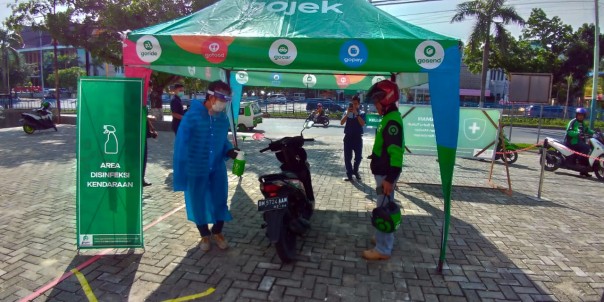 Petugas Gojek Pekanbaru tengah melakukan penyemprotan disinfectan pada kendaraan mitra driver di Pekanbaru.