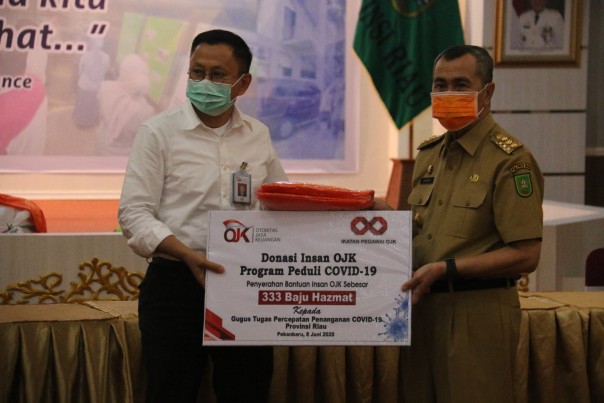 Kepala OJK Riau, Yusri menyerahkan bantuan berupa 333 baju hazmat yang diterima langsung oleh Gubernur Riau, Syamsuar