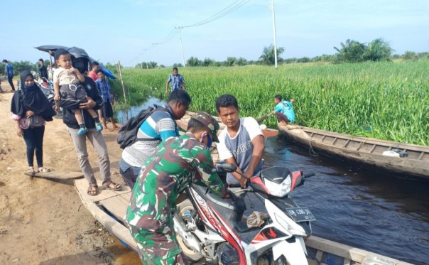 Tampak Babinsa Koramil 10/ Kunto Darussalam membantu warga yang melintas di jalan lintas Provinsi Riau Desa Sontang - Kasang Padang.