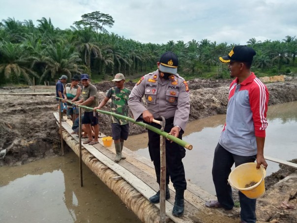 Bersama Mambangun Desa, Kapolsek Kerumutan Turun Langsung Gotong Royong di Desa Beringin Makmur