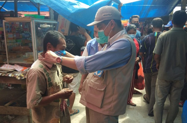 T. Edy Sabli memasangkan masker kepada pengunjung pasar