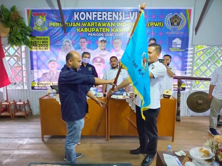 Akhir Yani menerima bendera PWI dari Sekretaris PWI Riau