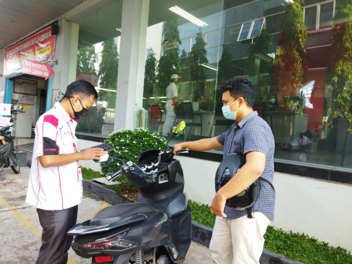 Poto Caption : Konsumen sedang melakukan pendaftaran service di AHASS di bantu oleh petugas AHASS. (Foto: Istimewa)