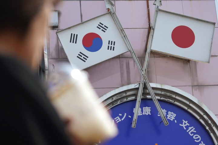 Seorang wanita berjalan melewati iklan yang menampilkan bendera Jepang dan Korea Selatan di sebuah toko di daerah Shin Okubo di Tokyo, Jepang, 2 Agustus 2019. (AP Photo) 