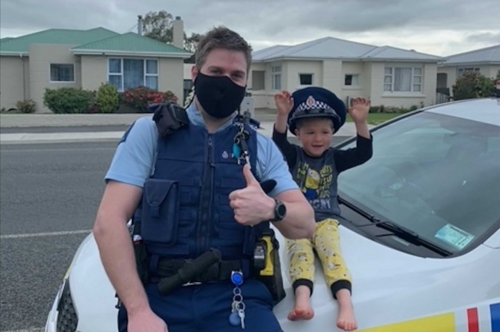 Seorang petugas yang diidentifikasi hanya sebagai Constable Kurt duduk di mobil patrolinya dengan seorang bocah lelaki berusia 4 tahun yang tidak disebutkan namanya, di kota Pulau Selatan Invercargill, Selandia Baru, 15 Oktober 2021. (Polisi NZ via AP)