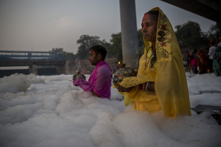 Umat ??Hindu India melakukan ritual di sungai Yamuna, ditutupi oleh busa kimia yang disebabkan oleh polusi industri dan domestik, selama festival Chhath Puja di New Delhi, India, 10 November 2021. (AP Photo)