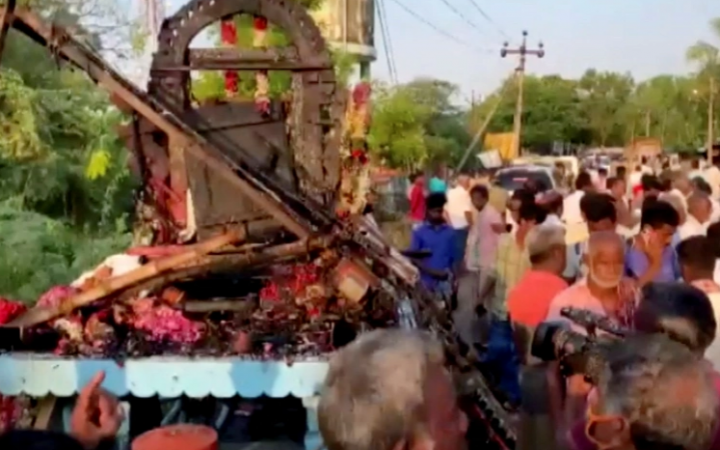 Orang-orang berkumpul di sekitar truk, yang dirancang sebagai kereta, yang rusak setelah kabel listrik bertegangan tinggi menimpanya di desa Kalimedu, distrik Thanjavur, India [ANI via Reuters]