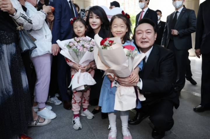 Presiden baru Korea Selatan Yoon Suk-yeol (kanan), dan istrinya Kim Keon-hee (kiri), berpose untuk foto setelah menerima karangan bunga dari anak-anak saat ia meninggalkan kediaman pribadinya untuk upacara peresmian [Yonhap via EPA]