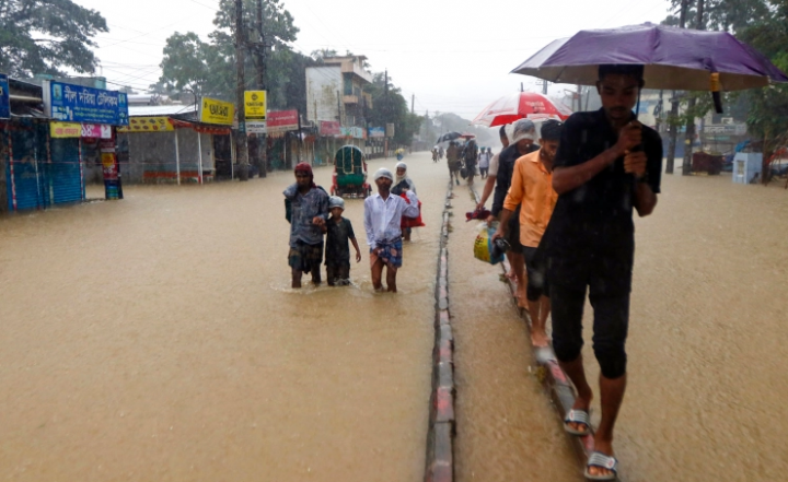 Orang-orang mengarungi jalan di daerah banjir setelah hujan lebat di Sylhet [AFP]